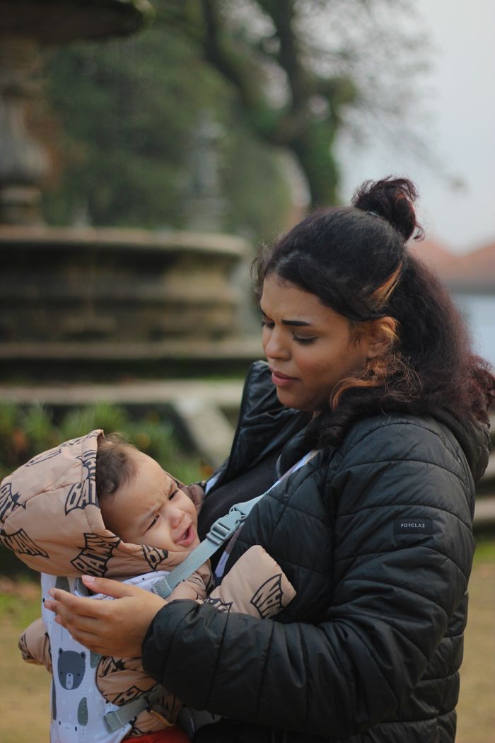 who-we-are A mother lovingly holds her baby in a park in Braga, Portugal, capturing a tender moment.